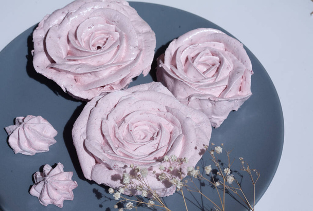 Πεντανόστιμα γλυκά ευάερα ζαχαρωτά με τη μορφή τριαντάφυλλου, παστέλ ροζ κέικ σε εστιατόριο, διακόσμηση για πιάτα και κέικ. - Φωτογραφία, εικόνα