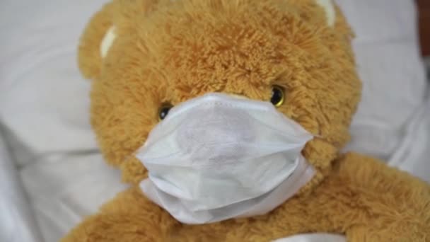 Un ours en peluche est couché dans un masque médical. L'ours est tombé malade.
. - Séquence, vidéo