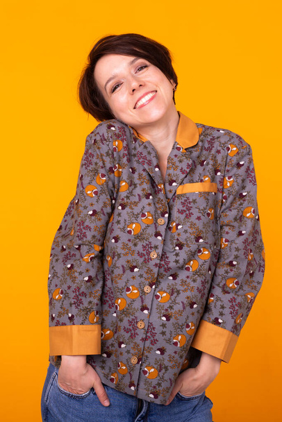 Portrait de mode fille assez cool en pyjama vêtements à la maison s'amuser sur fond jaune coloré
. - Photo, image