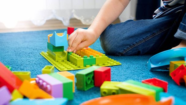 Closeup photo of child hand assemblind toy constructor and building a house - Photo, Image