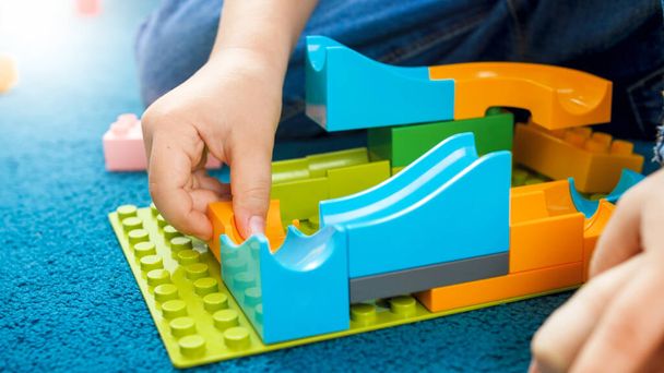 Closeup image of boys hand building toy track using constructor blocks - Photo, image