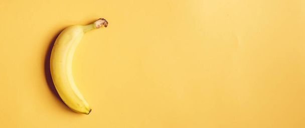 Fresh whole yellow banana on yellow background. Wide, banner format - Valokuva, kuva