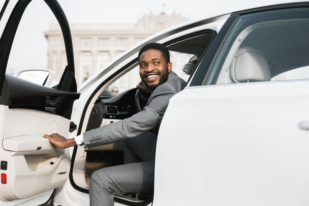 ビジネスマンが街で車から出る自動車ドアを開ける - 写真・画像