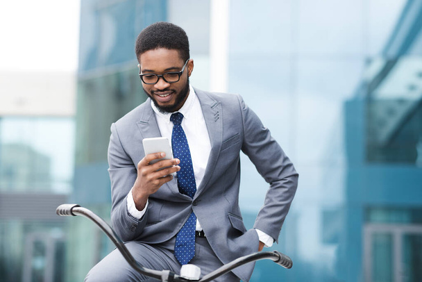 Guapo hombre de negocios mensajes de texto en el teléfono sentado en bicicleta - Foto, Imagen