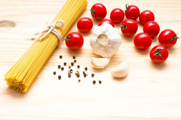 Ingredientes de pasta en tablero de madera, tomates cereza, especias, albahaca, ajo, cocina de alimentos, cocina italiana, fondo blanco
 - Foto, Imagen