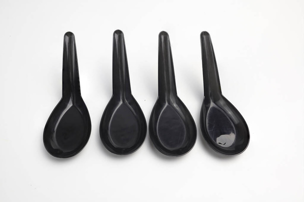 Черные пластиковые ложки расположены на белом фоне
 - Фото, изображение