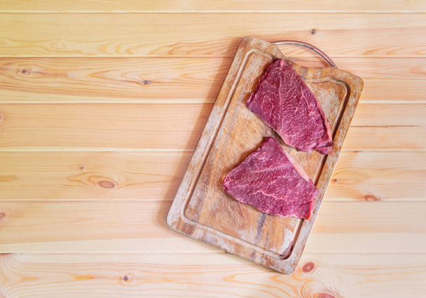 Raw fresh marbled meat Black Angus Steaks on cutting board on wooden table. Top view, copy space. - Valokuva, kuva