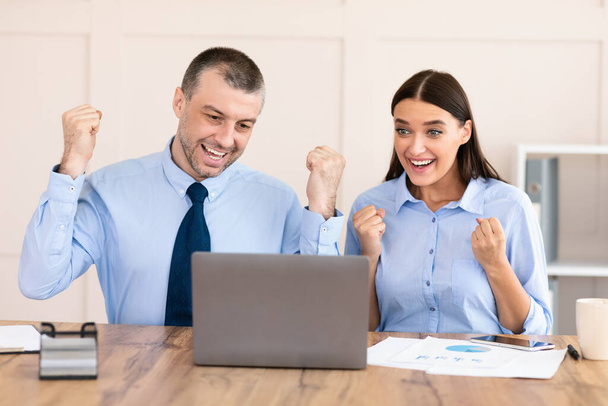 Businessman And Businesswoman Shaking Fists Celebrating Business Success In Office - Фото, изображение