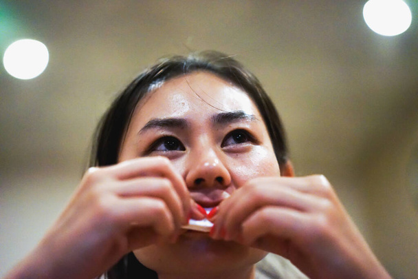 Jeune fille asiatique souriante heureuse essuie la bouche après avoir mangé de la nourriture au restaurant, tissu blanc, bonne manière à la table, bonheur, mise au point sélective, bokeh flou, film noir bruit grain - Photo, image