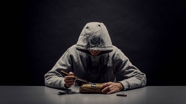 man is a drug addict sitting at the table makes drugs. The concept of social problems of drug addiction and crime. - Foto, Imagen