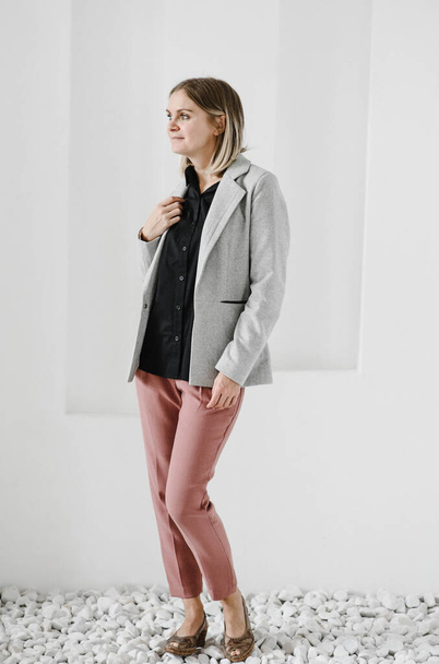 girl in a gray jacket with a black shirt and full-length powdery trousers posing in the studio. dress code. business.photo in the studio, lifestyle, blonde in the office - Фото, изображение