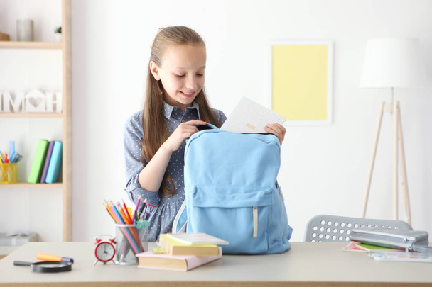 Cute cheerful schoolgirl puts stationery in a backpack. Preparation for school. Back to school. School Backpack Day - Zdjęcie, obraz