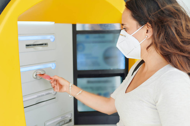 Woman with antiviral mask at ATM - Foto, afbeelding