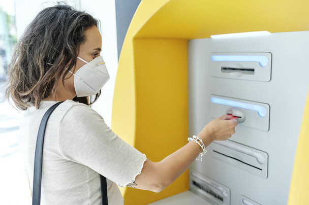 Vrouw met antiviraal masker bij ATM - Foto, afbeelding