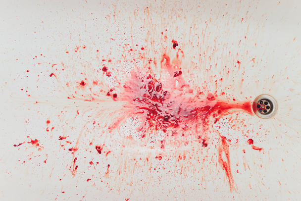Fresh red blood splat on white porcelain with specks from the impact. Copy space area for horror themed concepts and ideas. - Photo, Image