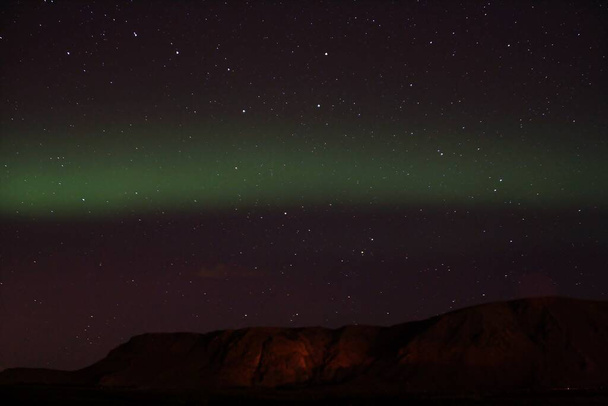 Τα βόρεια φώτα στο Selfoss και το λόφο Inglfsfjall στο παρασκήνιο στην Ισλανδία. - Φωτογραφία, εικόνα