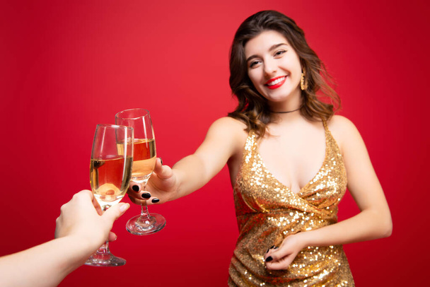 Sexy woman in gold dress with with red lipstick and with champagne in hand over holiday red background. Concept of a New Year holiday, Birthday party. - Photo, Image