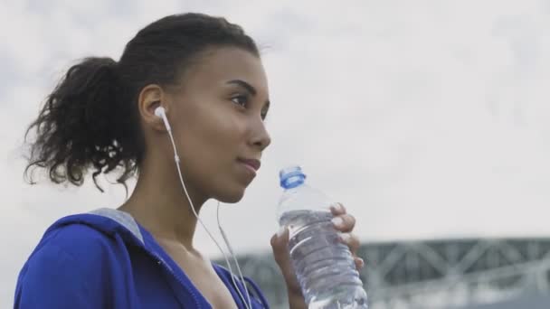 Afro-americano corridore donna acqua potabile dopo la corsa. Ritratto Fitness Donna Acqua potabile Dalla Bottiglia. - Filmati, video