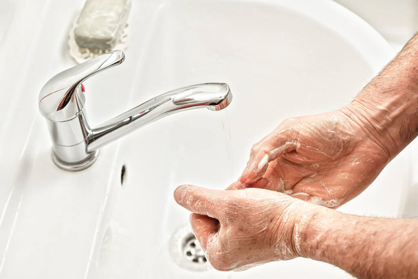Senior elderly man his hands under tap water faucet, detail photo. Can be used as hygiene illustration concept during coronavirus / covid-19 outbreak prevention - Fotó, kép
