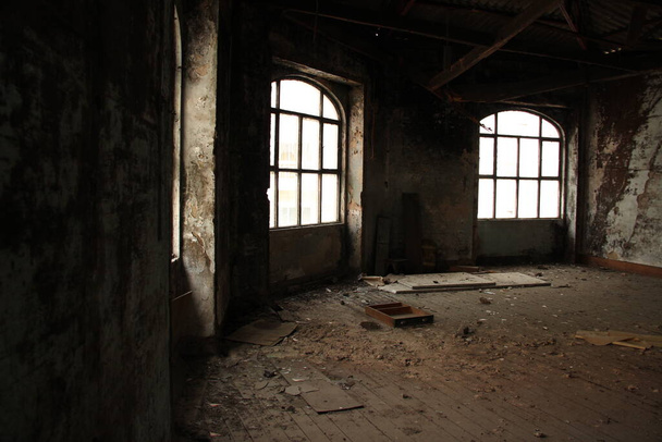 Ahşap zeminde kırık mobilyalar, toprak ve döküntüler olan büyük terk edilmiş kirli bir odanın içinde.. - Fotoğraf, Görsel