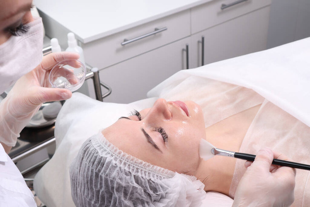 Женщина на ресепшене у косметолога. Косметические процедуры для лица и шеи. Понятие ухода за кожей лица и шеи
 - Фото, изображение