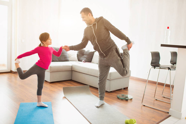 father and daughter are training at home. Workout in the apartment. Sports at home. They do exercises with yoga or Pilates. - Fotó, kép