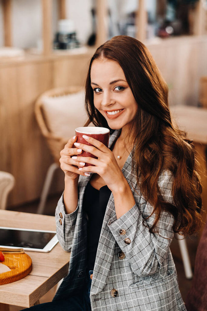 a girl drinks coffee in a coffee shop, beautiful hair of a girl - Foto, Imagem