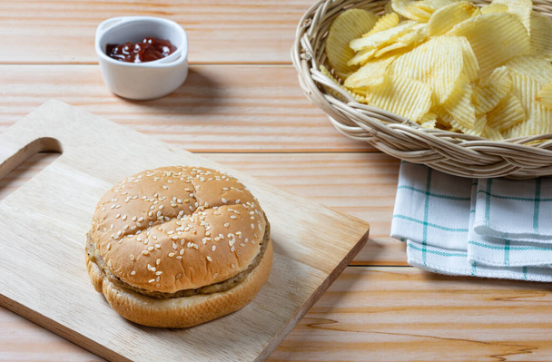 Lahodný nízkotučný hamburger a bramborové lupínky v košíku s kečupem. Připraveno k jídlu. - Fotografie, Obrázek