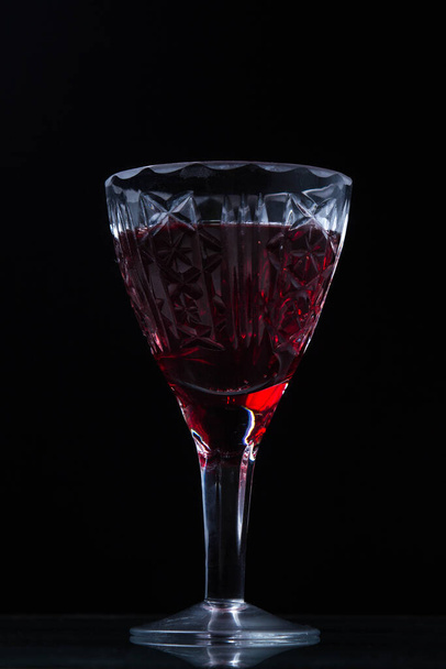 Red wine in a crystal glass. Photo on a black background - Valokuva, kuva
