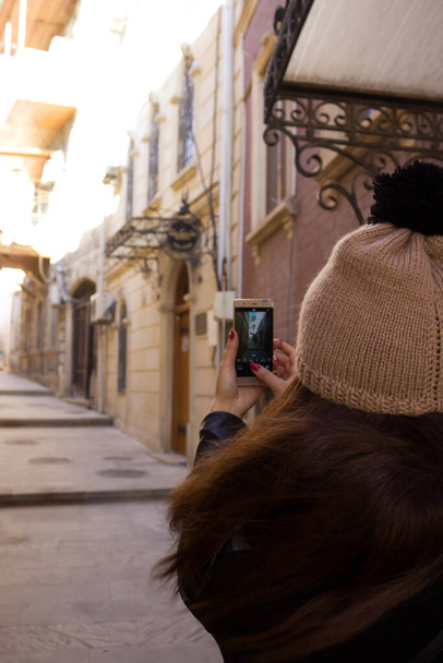 Girl takes a picture of the city in the winter on a phone camera - Photo, image