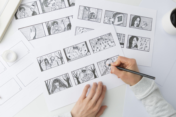 Las manos dibujan con un lápiz el guion gráfico para la película. El artista dibuja personajes de dibujos animados
. - Foto, Imagen