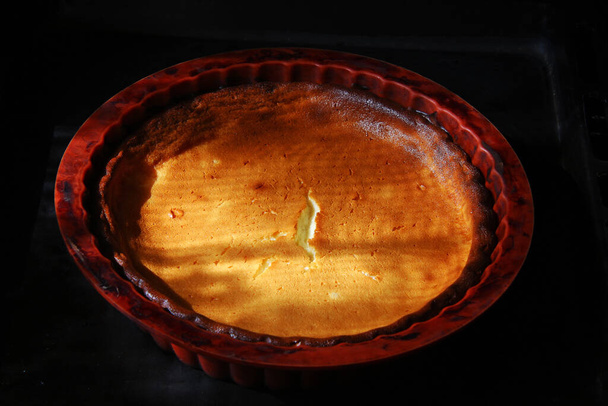 Fırındaki silikon kalıbında çatlak bir kabukla ev yapımı, pembe peynirli kek. - Fotoğraf, Görsel