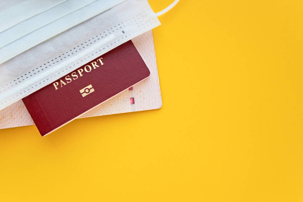 Passports with medical mask on a yellow background with copy space. Ban on visits to other countries - Foto, imagen