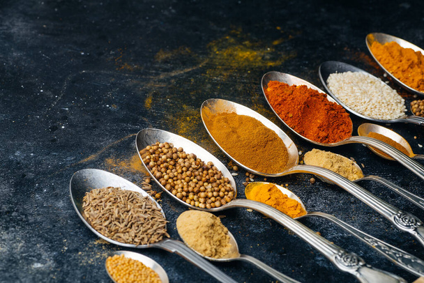 Spices in spoons background. Varieties of spices (turmeric, pepper, chili, coriander, cinnamon) and peppers for cooking. Culinary food concept. - Fotografie, Obrázek