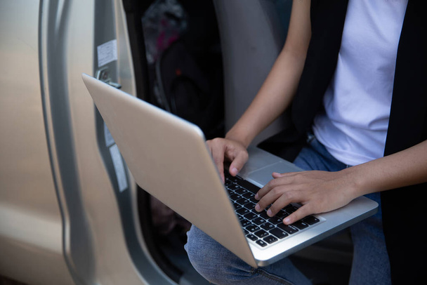 Schöne Geschäftsfrau benutzt Laptop während sie im Auto sitzt. - Foto, Bild