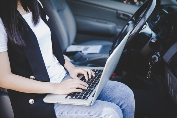 Belle femme d'affaires utilisant un ordinateur portable tout en étant assis dans la voiture
. - Photo, image