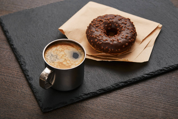 still life of an iron cup with coffee and donuts, on a brown wooden table . dark retro still life . old-fashioned style - Valokuva, kuva
