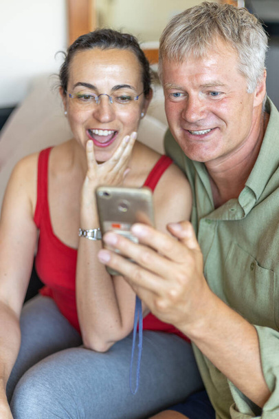 Happy middle-aged couple looking a mobile phone - Foto, Imagen