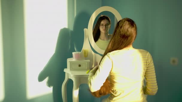Nettes Mädchen mit Brille achtet auf ihre Haare, schaut in den Spiegel - Filmmaterial, Video