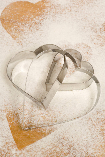 Három szív alakú keksz vágó készlet lisztporos háttéren - Fotó, kép