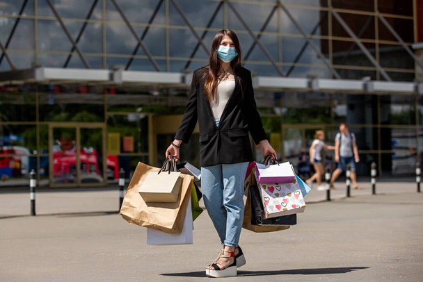 girls in medical mask rejoices with shopping near the mall - Фото, зображення