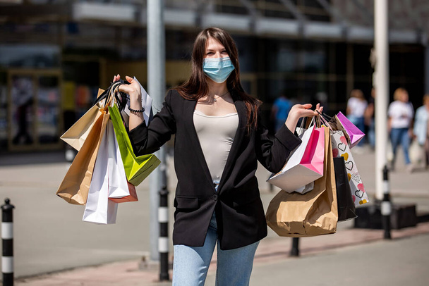 girls in medical mask rejoices with shopping near the mall - Photo, image