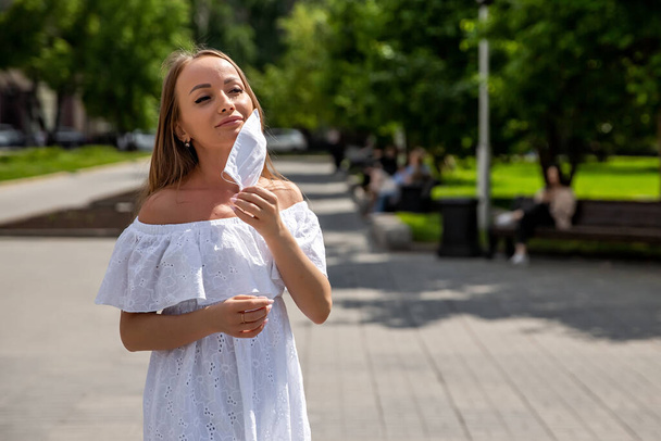 girl in the park takes off a medical mask - Фото, изображение
