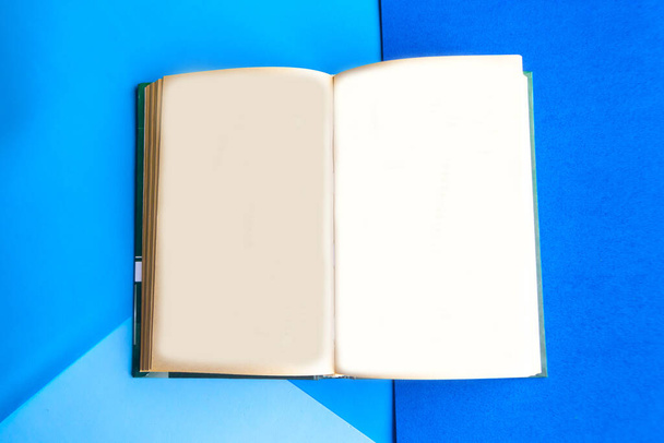 Відкрити макетну книгу на геометрично синьому пастельному фоні
 - Фото, зображення