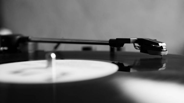 Black and white vinyl needle stylus on rotating black vinyl disk with copy space. Turntable vinyl record player. - Photo, Image