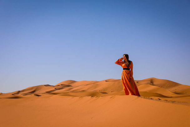 Beautiful young girl in Moroccan dress in Sahara desert. - Photo, Image