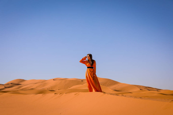 Beautiful young girl in Moroccan dress in Sahara desert. - Photo, image