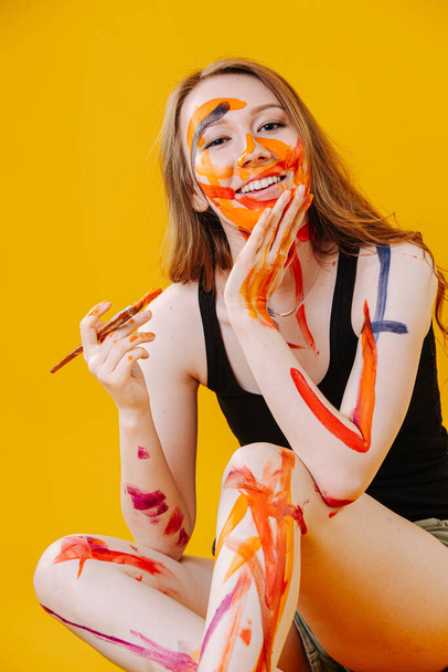 Playful twenty year old girl smiling at camera, she randomly painted her body - Foto, afbeelding