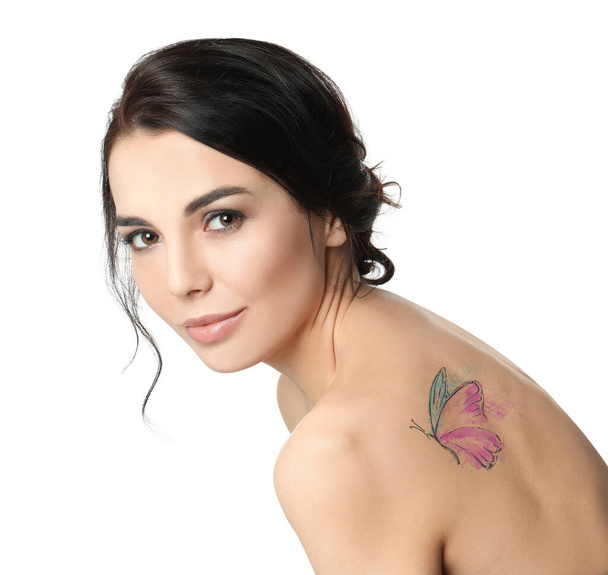 Jonge vrouw met kleurrijke tatoeage van vlinder op haar lichaam tegen witte achtergrond - Foto, afbeelding