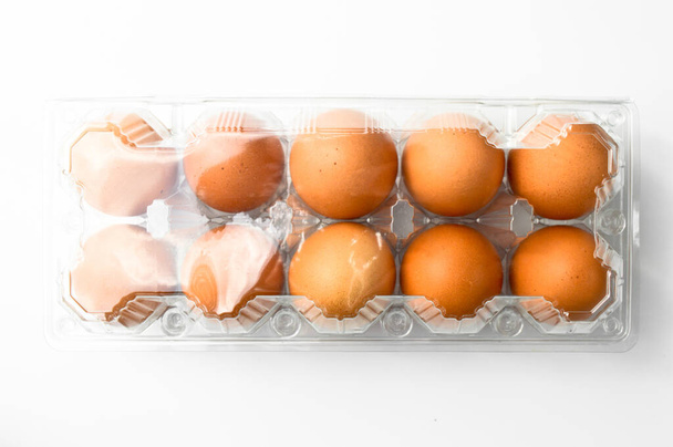 Huevos marrones orgánicos frescos en un paquete de caja de plástico, aislados sobre fondo blanco
 - Foto, imagen